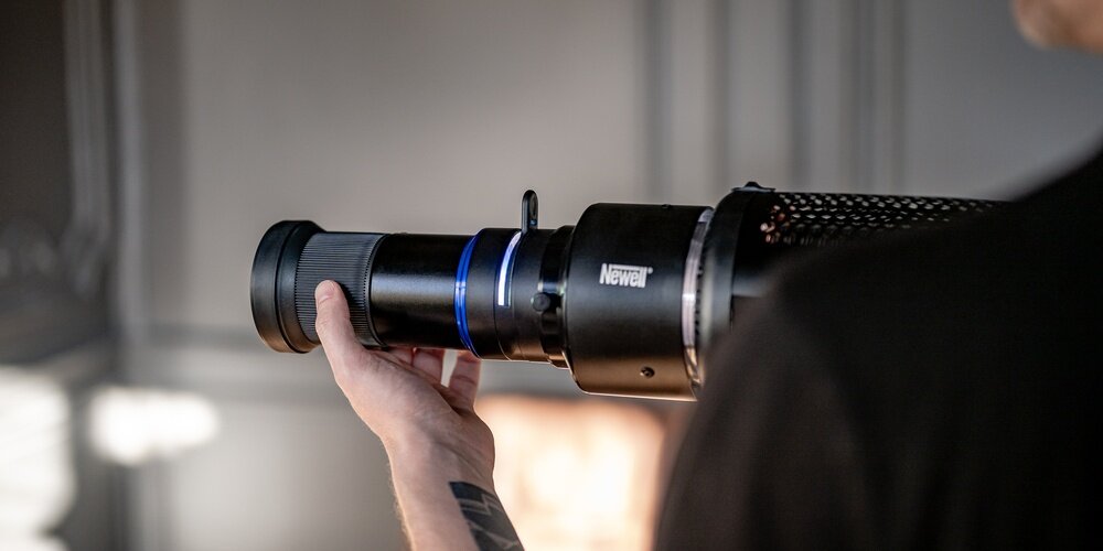 Fotograf trzyma strumienicę Newell Perseo-33, regulując ustawienie soczewki w celu precyzyjnego skierowania światła