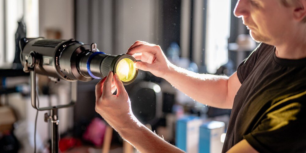 Fotograf zakłada żółty filtr kolorystyczny na strumienicę Newell Perseo-33, dostosowując barwę emitowanego światła