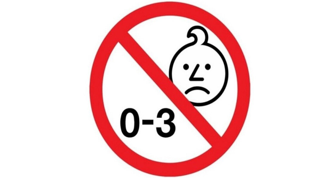 Symbol zakazu z czerwoną obwódką, wewnątrz którego znajduje się smutna twarz dziecka i napis \'0-3\'.