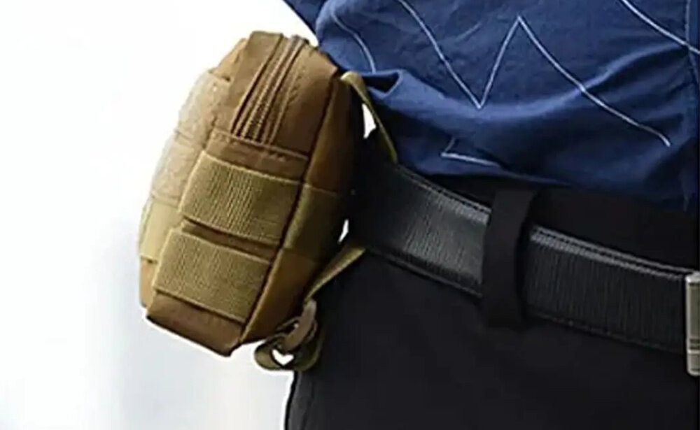 Saszetka EXTRALINK Military Molle Mil-663 osoba zbliżenie na pas osoba ma założoną saszetkę na pasie waga około 85 g nie obciąża użytkownika wymiary 180 × 130 × 40 mm komfort praktyczny dodatek