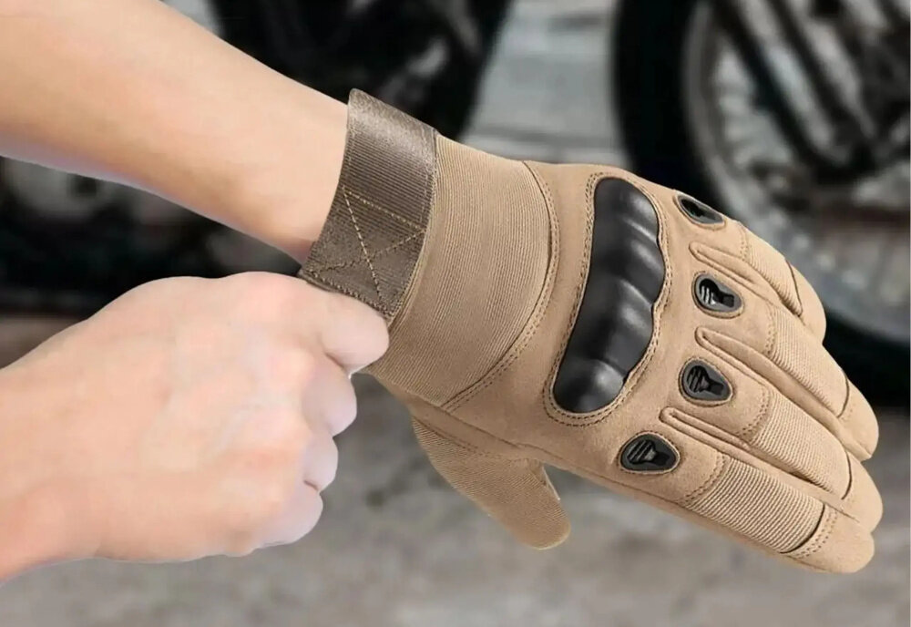 Rękawice taktyczne EXTRALINK MIL-696 (rozmiar L) Brązowy osoba zakłada rękawice na dłonie w tle motor specjalne antypoślizgowe wstawki kontrola nad narzędziami sprzętem bronią większa precyzja i bezpieczeństwo minimalizuje ryzyko przypadkowego poślizgu i kontuzji dłoni