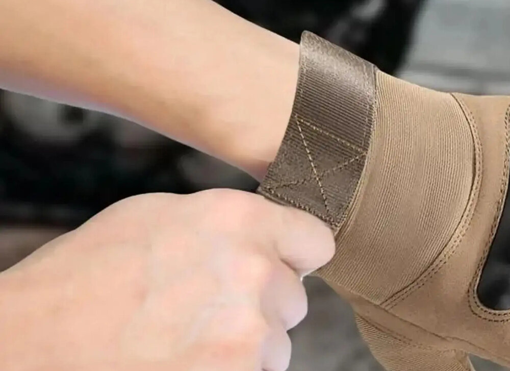 Rękawice taktyczne EXTRALINK MIL-696 (rozmiar L) Brązowy zbliżenie na rzep osoba trzyma rzep w palcach szeroka taśma na rzep stabilizuje rękawice na dłoni usztywnia nadgarstek regulowane zapięcie dopasowanie do obwodu nadgarstka regulacja w zakresie 23–24 cm