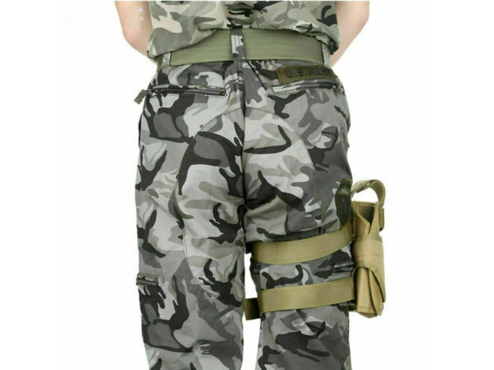 Kabura na broń EXTRALINK Military MIL-1117 białe tło osoba stoi tyłem do nogi ma przytwierdzoną kaburę z tkaniny 600D Oxford wytrzymałość na przetarcia i warunki terenowe trwałość waga 326 g kolor khaki