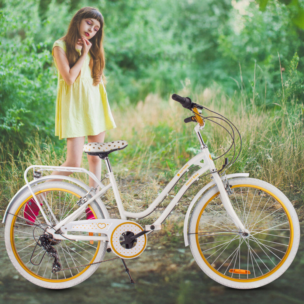 Rower młodzieżowy SUN BABY Heart Bike 24 cale dla dziewczynki Biało-złoty rower na trawie oparty o stopkę w tle dziewczynka na łące bagażnik łatwy transport odciążenie pleców wysoki komfort podróży solidna konstrukcja odporne na warunki atmosferyczne materiały