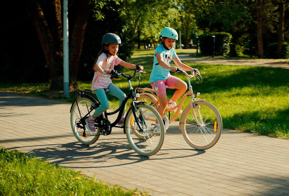 Rower młodzieżowy SUN BABY Flower Bike 24 cale dla dziewczynki Czarny dwoje dzieci jedzie na rowerach po drodze rowerowej w tle trawa i drzewa wysoki komfort jazdy brak uczucia dyskomfortu odpowiednia pozycja ciała uchwyty z antypoślizgowego materiału regulacja w zakresie od 95 do 98 cm