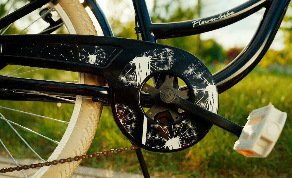 Rower młodzieżowy SUN BABY Flower Bike 24 cale dla dziewczynki Czarny zbliżenie na osłonę łańcucha w tle trawa osłona łańcucha kwiatowa grafika zabezpiecza łańcuch przed brudem błotniki elegancki wygląd osłaniają odzież