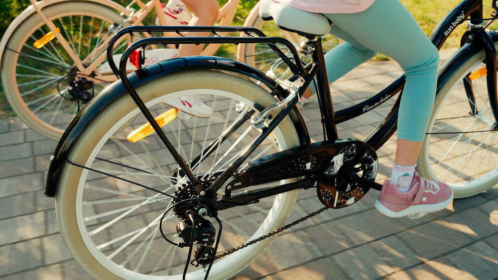 Rower młodzieżowy SUN BABY Flower Bike 24 cale dla dziewczynki Czarny dwie osoby jadą na rowerach zbliżenie na bagażnik w tle trawa bagażnik łatwy transport odciążenie pleców wysoki komfort podróży solidna konstrukcja odporne na warunki atmosferyczne materiały