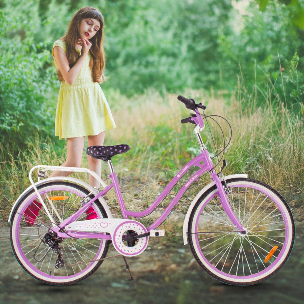 Rower młodzieżowy SUN BABY Heart Bike 24 cale dla dziewczynki Fioletowy rower na trawie oparty o stopkę w tle dziewczynka na łące bagażnik łatwy transport odciążenie pleców wysoki komfort podróży solidna konstrukcja odporne na warunki atmosferyczne materiały