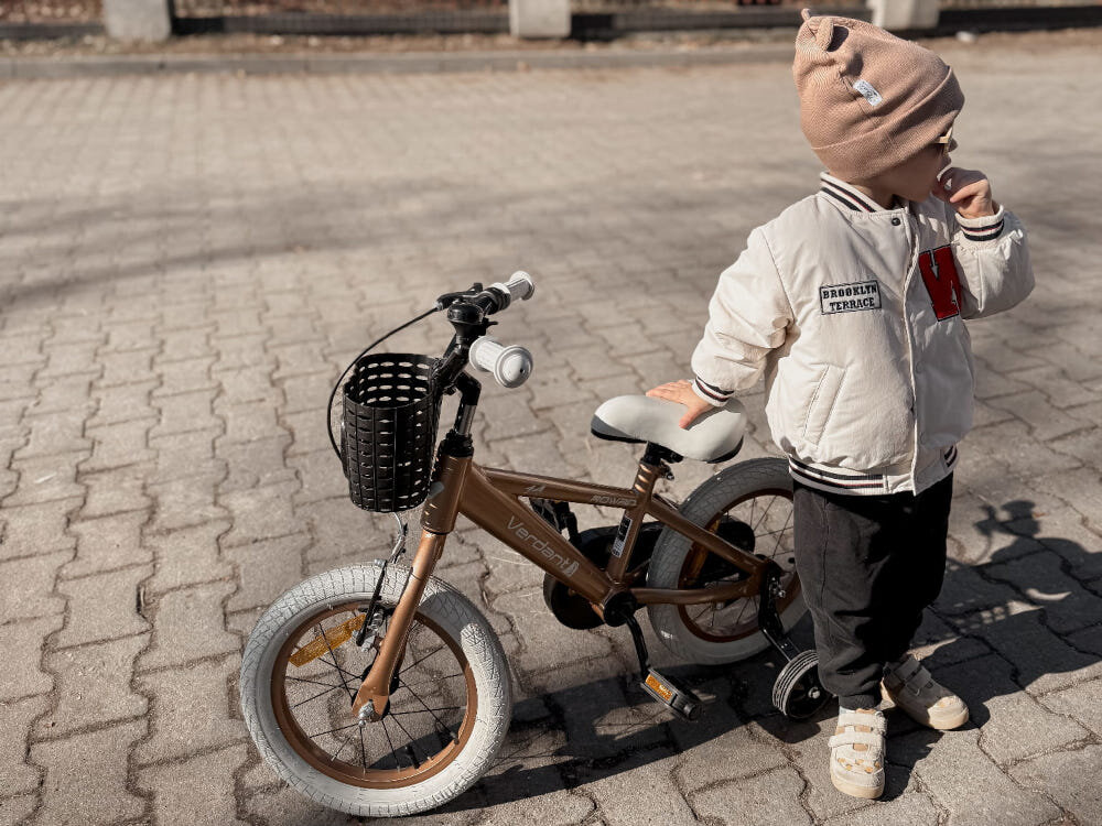 Rower dziecięcy SUN BABY Verdant Rowan 14 cali dla chłopca Cappuccino chodnik dziecko stoi obok rowerka opiera się dłonią o siodełko odpowiednio wyselekcjonowane materiały stalowa 8,25-calowa rama dostosowana do najmłodszych geometria ponadprzeciętna odporność na uszkodzenia mechaniczne i działanie czynników zewnętrznych wybór rozmiaru ramy Twój wzrost mierzony w zrelaksowanej pozycji typ dla dzieci o wzroście od 95 do 105 cm