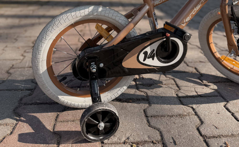 Rower dziecięcy SUN BABY Verdant Rowan 14 cali dla chłopca Cappuccino chodnik zbliżenie na kółka boczne i osłonę łańcucha boczne kółka asekurują dziecko w początkowej fazie nauki boczne kółka można łatwo usunąć stylowa osłona łańcucha zabezpiecza łańcuch przed brudem