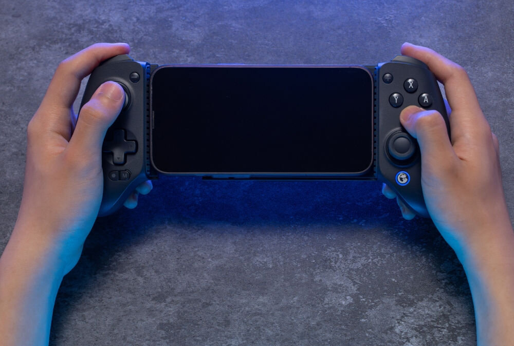 Kontroler GAMESIR G8+ Bluetooth z uchwytem na telefon
                z zamontowanym telefonem w dłoniach urządzenia mobilne switch tablety pc przyciski i drążki stworzony do podróży kanapy granie gdziekolwiek