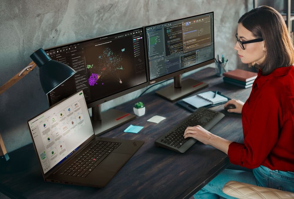 Specjalistka w czerwonej bluzce pracująca z laptopem Lenovo ThinkPad podłączonym do dwóch zewnętrznych monitorów z danymi naukowymi - Procesor serii Intel Core Ultra 