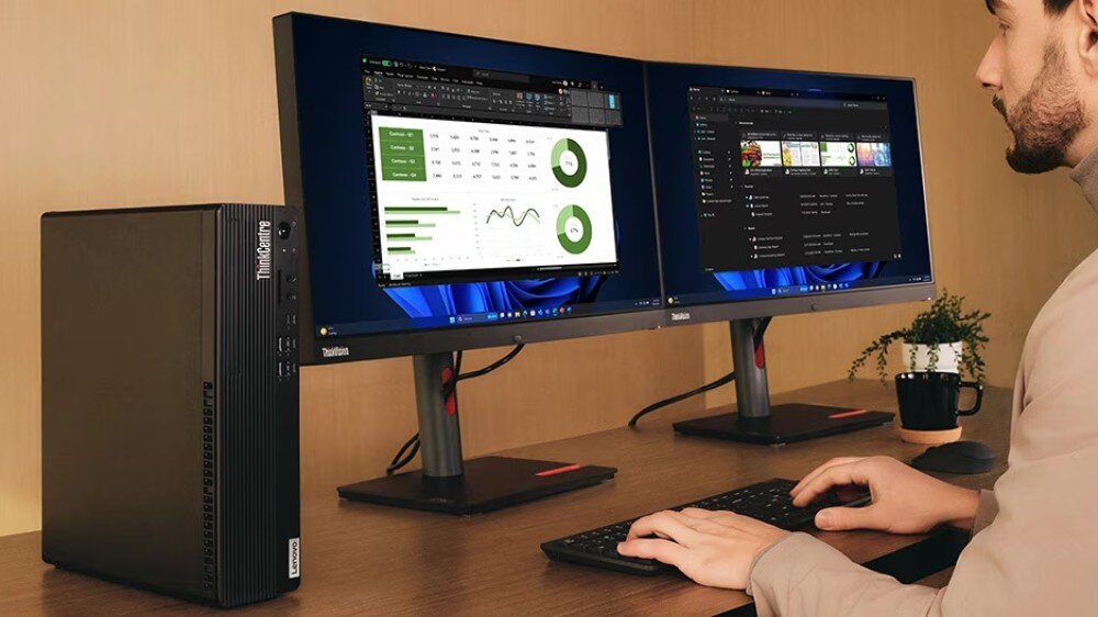 Komputer LENOVO ThinkCentre M75S Gen 5 Mężczyzna siedzi przy biurku i pracuje na komputerze z dwoma monitorami. Po lewej stronie stoi pionowa obudowa komputera, opis