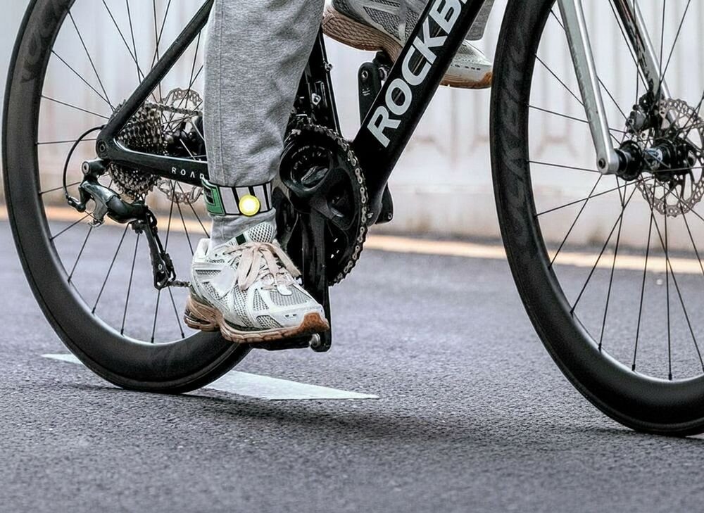 Opaska odblaskowa ROCKBROS 49210009001, lekka, kostka, noga, komfort, Zbliżenie na nogę rowerzysty z odblaskową opaską.