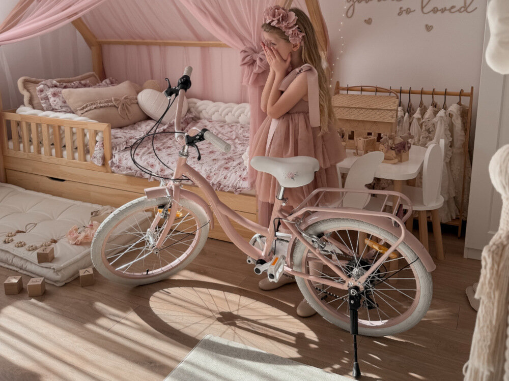 Rower dziecięcy SUN BABY Flower bike 20 cali dla dziewczynki Różowy pokój rower stoi oparty o stopkę dziewczynka stoi obok roweru bagażnik łatwy transport odciążenie pleców wysoki komfort podróży solidna konstrukcja odporne na warunki atmosferyczne materiały