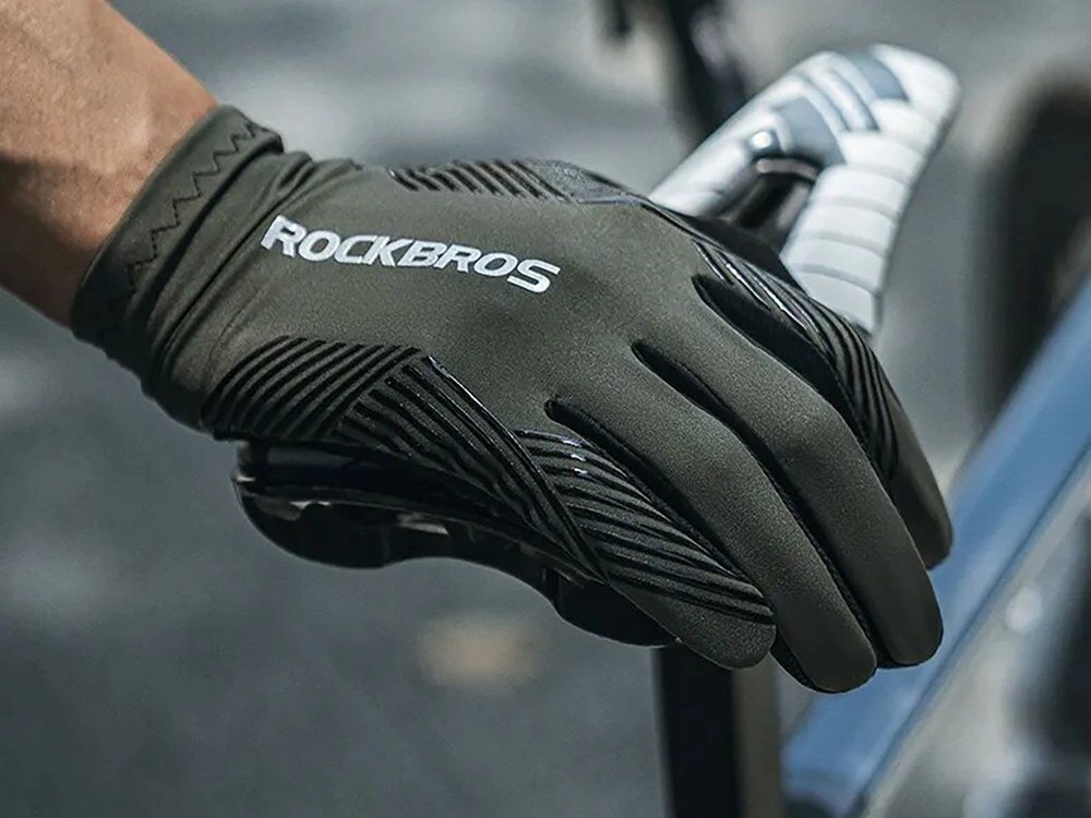 Czarna rękawiczka Rockbros trzymająca kierownicę roweru, zbliżenie na wzór antypoślizgowy i logo marki.