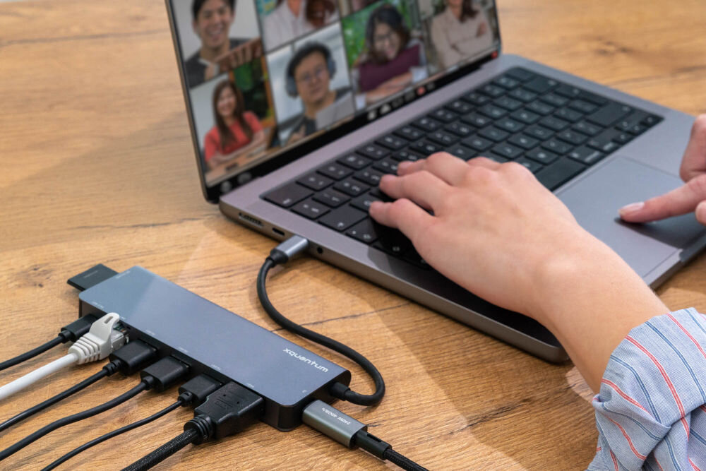 Hub USB XQUANTUM UH300 9w1 hub podpięty do komputera przez port USB-C obok 3 wtyczki USB-A wtyczka lan wtyczka usb-c karta mikro sd i sd hdmi ułożone obok portów adaptera