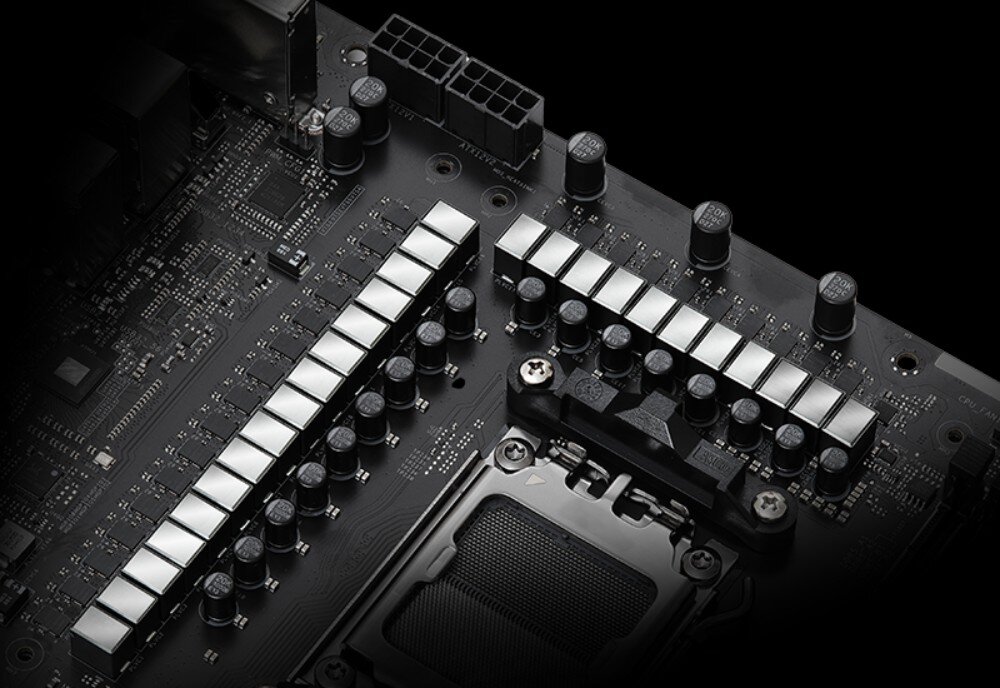 Płyta główna ASROCK X870E Taichi Zbliżenie na sekcję zasilania płyty głównej z dwiema rzędami srebrnych dławików i czarnymi kondensatorami, układ zasilania, fazy, złącze