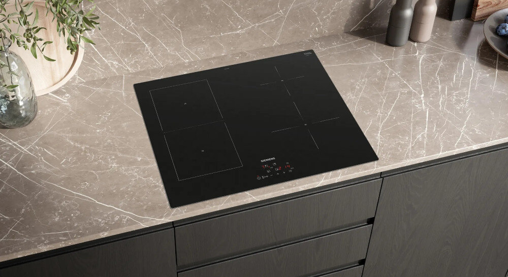 PŁYTA SIEMENS EE611BPB5E Na zdjęciu widoczna jest czarna płyta indukcyjna Siemens wkomponowana w jasny, marmurowy blat kuchenny. Minimalistyczny design z czterema strefami grzewczymi i dyskretnym panelem sterowania podkreśla charakter zabudowy