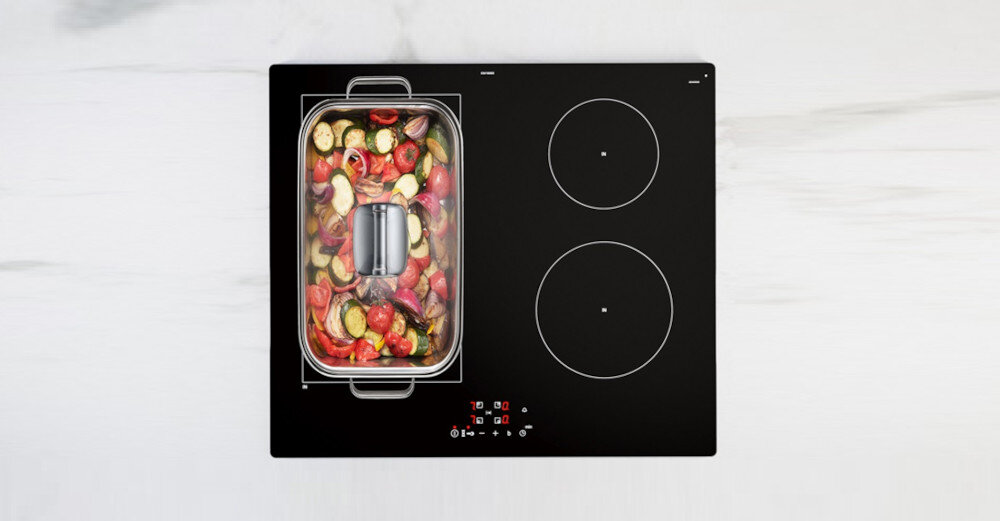 PŁYTA SIEMENS EE611BPB5E Na zdjęciu widoczna jest czarna płyta indukcyjna Siemens z dużą, prostokątną strefą po lewej stronie, na której stoi wypełniona warzywami brytfanna z pokrywką. Po prawej stronie znajdują się dwa okrągłe pola grzewcze, a u dołu centralnie umieszczony jest czerwony, dotykowy panel sterowania Strefa combiZone combiZone połączenie stref dużych garnków wygodne efektywne pełna kontrola oszczędność czasu komfort