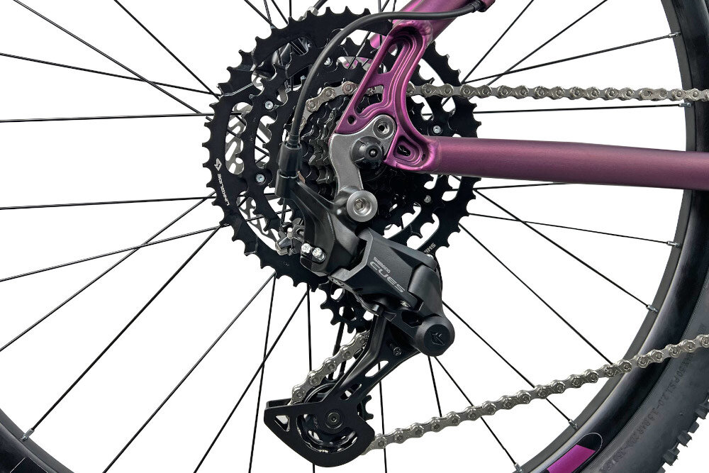 Rower górski MTB INDIANA X-Pulser 3.7 D19 27.5 cala damski Fioletowy zbliżenie na tylną przerzutkę przerzutki marki przerzutki marki SHIMANO 9 biegów duża wytrzymałość sprawne działanie zmiana biegów jest płynna i bezproblemowa tylny napęd SHIMANO CUES niewiarygodnie płynna szybka zmiana przełożeń wytrzymałość