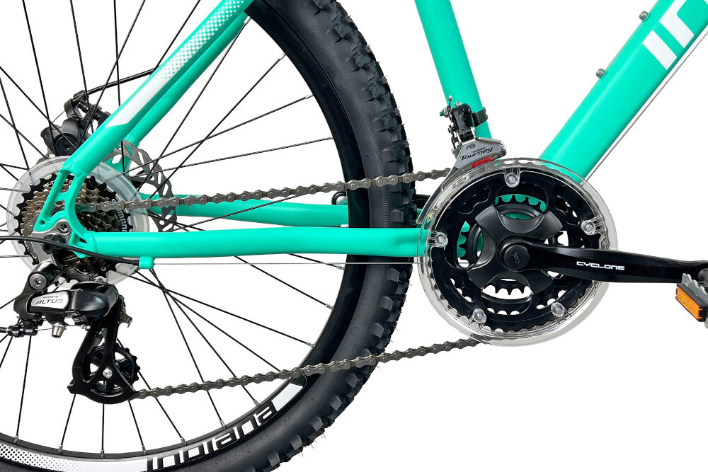 Rower górski MTB INDIANA X-Pulser 2.6 D15 26 cali damski Miętowo-biały zbliżenie na korbę wolnobieg i łańcuch lekka wydajna konstrukcja korby korba CYCLONE typu 24/34/42T-170 CTL3 wolnobieg SHIMANO typu MF-TZ500-7 14x28 7V solidność wytrzyma bardzo duży nacisk na pedały