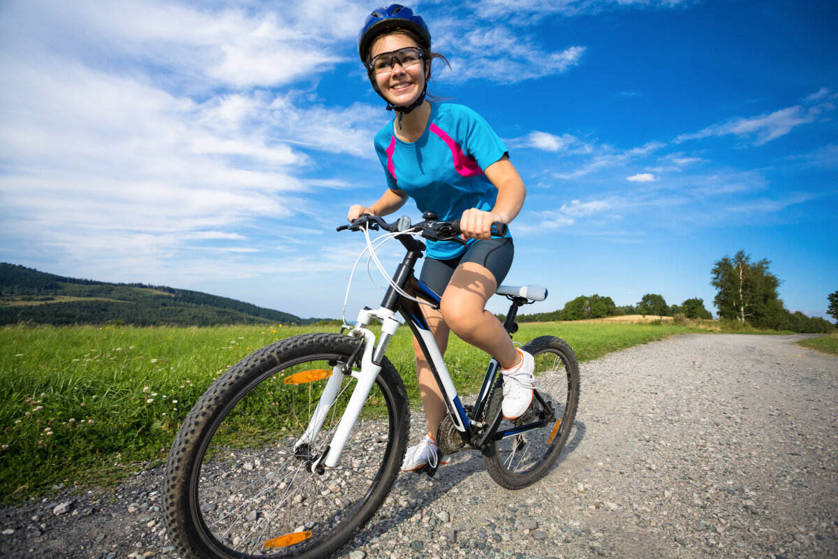 Rower crossowy INDIANA X-Cross 2.0 D21 damski Czarno-różowy osoba jedzie po drodze na tle pola i nieba środek codziennego transportu relaks pasja uniwersalność