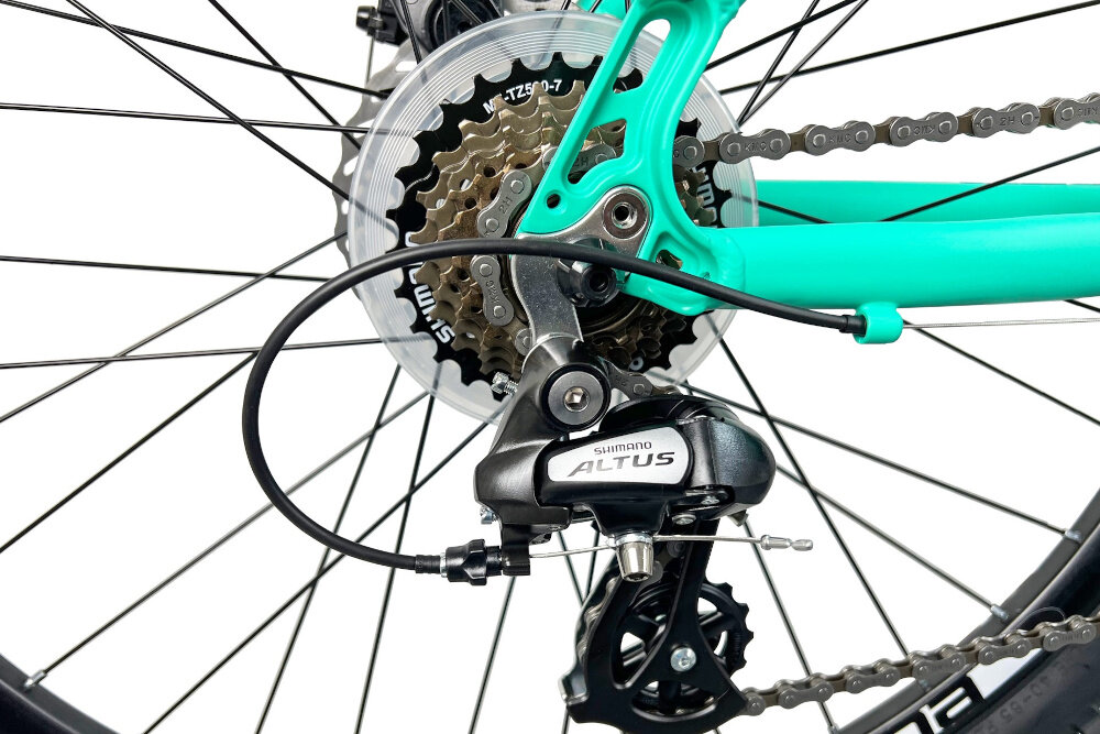 Rower górski MTB INDIANA X-Pulser 2.6 D19 26 cali damski Miętowo-biały zbliżenie na tylną przerzutkę przerzutki marki SHIMANO duża wytrzymałość sprawne działanie zmiana biegów jest płynna i bezproblemowa przednia przerzutka SHIMANO Tourney tylna przerzutka SHIMANO Altus technologia Shadow przerzutka jest schowana i mniej narażona na uszkodzenia 21 biegów