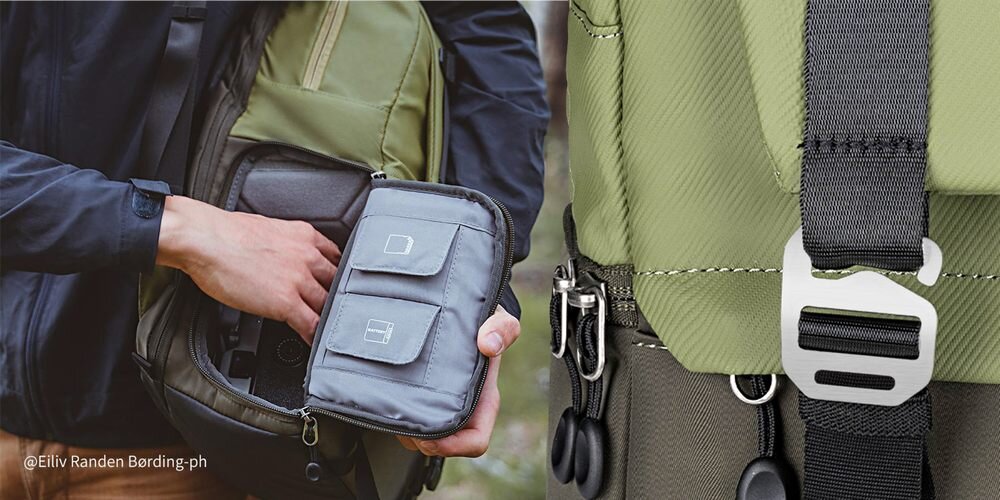 Otwarty plecak z boczną kieszenią na zamek; dłoń wyciąga aparat, obok metalowa klamra i karabińczyki