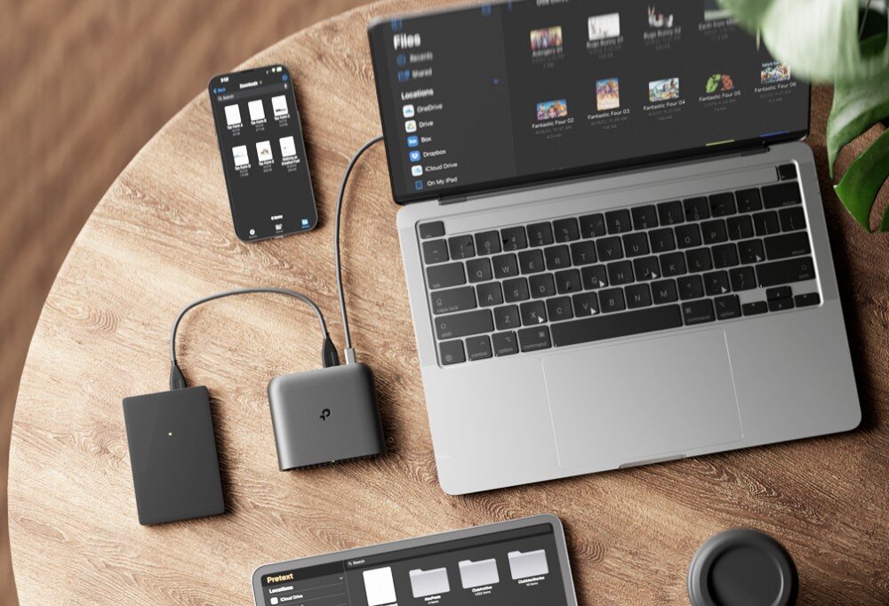 Router TP-LINK TL-WR1502X Na drewnianym biurku znajduje się laptop, smartfon oraz router podłączony do zewnętrznego dysku twardego. Na ekranach widać otwarte foldery z plikami, udostępnianie plików