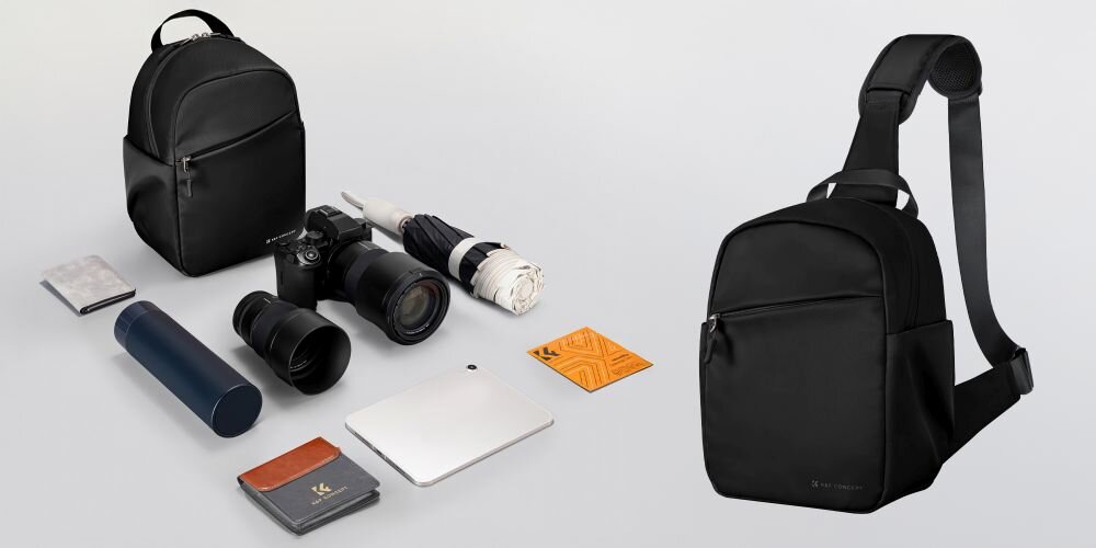 Na obrazie widoczne są dwa czarne plecaki oraz różne akcesoria fotograficzne, takie jak aparat, obiektywy, termos, parasol i notes. Plecak po prawej stronie ma jedną szelkę i widoczne logo \'K&F CONCEPT\'.