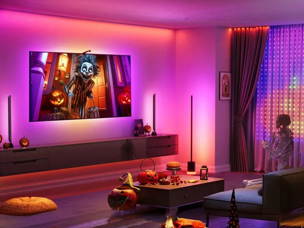 Lampa podłogowa GOVEE H607C, kolor, wnętrze, styl, klimat, Pokój w atmosferze Halloween: TV z filmem o duchach, dynie, figurki zombie i pajęczyny, oświetlone różowo-fioletowym światłem od dwóch lamp podłogowych Govee RGBIC, z różowymi LED-ami na suficie i suficie, tworzącym straszną, kolorową scenę
