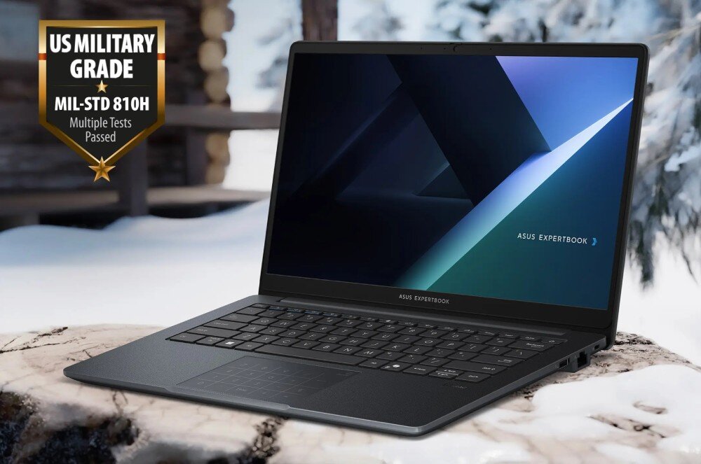 Laptop ASUS ExpertBook B1403CVA-S60475X Laptop na drewnianej powierzchni w zimowym otoczeniu. W lewym górnym rogu oznaczenie standardu wytrzymałości wojskowej MIL-STD 810H, wytrzymałość, standard MIL-STD-810H, obudowa