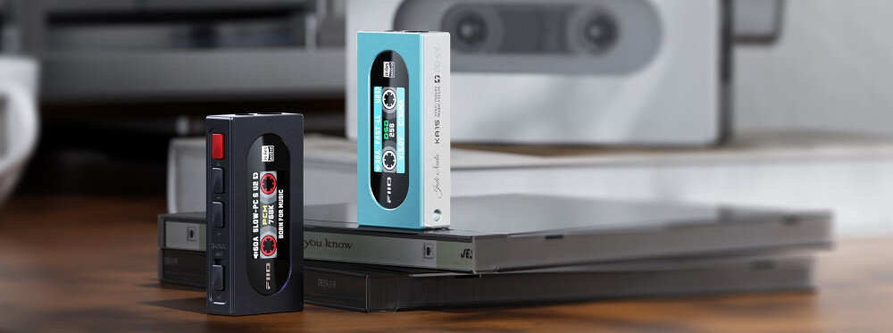 Wzmacniacz słuchawkowy FIIO KA15 mobilny DAC AMP audio hi-fi retro design, wzmacniacze słuchawkowe w dwóch kolorach, jedno urządzenie stojące na pudełu od płyty CD, drugie zaś na stole obok pudełek
