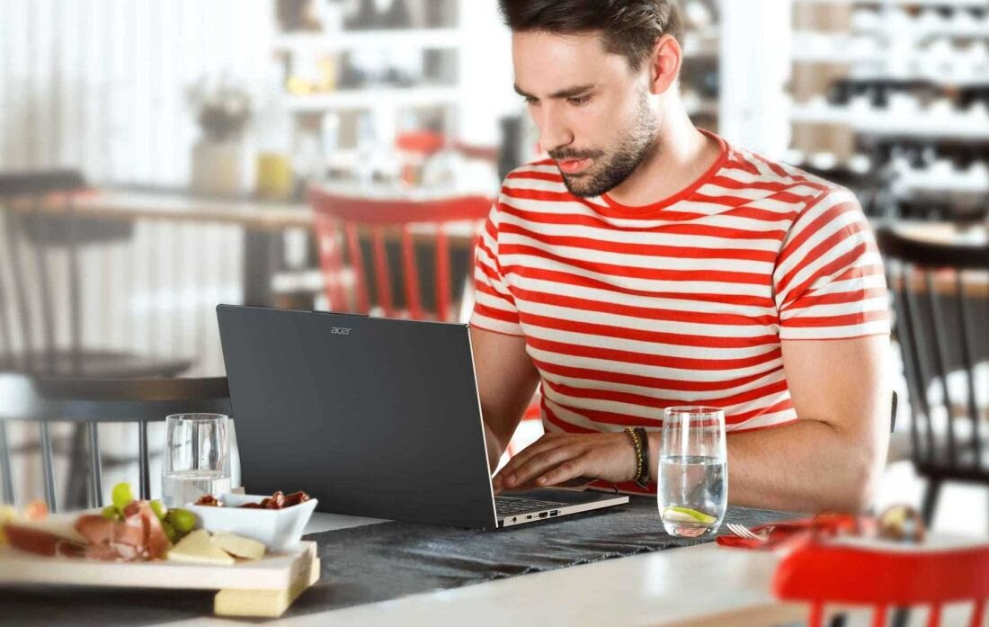 Laptop ACER Aspire 15 - Mężczyzna przy stole, korzystający z laptopa ACER Aspire 15, z wyrazem koncentracji na twarzy.