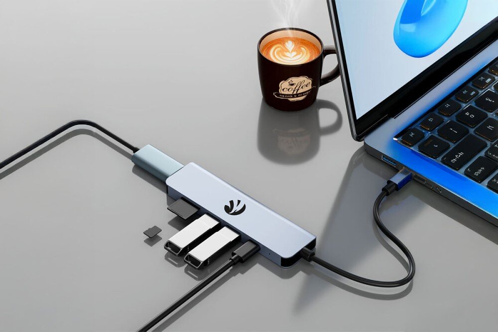 Hub HAWK HW-HUB601 6w1 Hub USB-C podłączony do laptopa na szklanym biurku. Do urządzenia wpięte są dwa pendrive’y oraz karta pamięci, USB-C, Power Delivery, ładowanie, moc