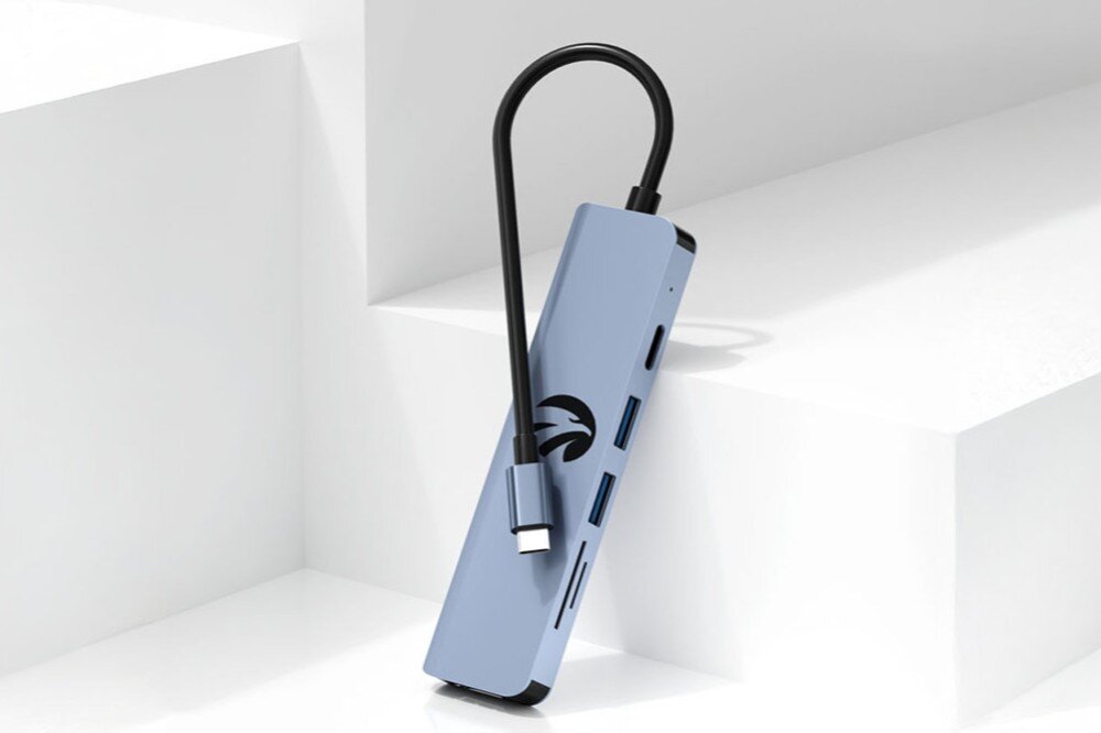 Hub HAWK HW-HUB601 6w1 Hub oparty o białą powierzchnię schodków. Przewód USB-C jest owinięty wokół urządzenia, obudowa materiał, wygląd