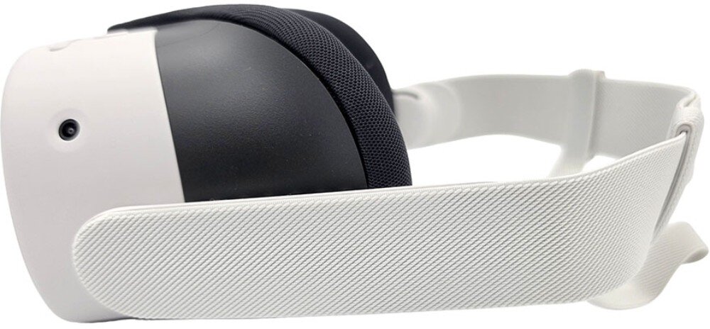 Na obrazie widoczne są gogle VR w kolorze białym z czarnymi elementami, posiadające regulowany pasek. Gogle mają minimalistyczny design z jednym widocznym przyciskiem lub czujnikiem na boku.