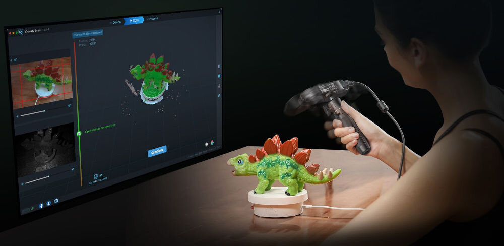 Skaner 3D CREALITY CR-Scan Ferret SE  prezentacja urządzenia podczas korzystania skanowanie figurki dinozaura w tle monitor z włączonym programem technologia śledzenia wsparcie płynnego skanowania ogranicza wpływ drgań na wynik