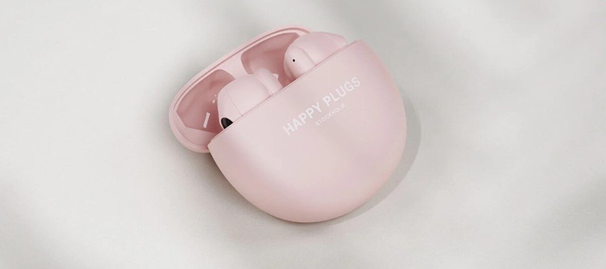 Słuchawki douszne HAPPY PLUGS Joy Lite - Sterowanie dotykowe, słuchawki z otwartym etui ładującym leżace na tkaninie