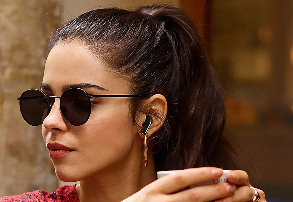 Słuchawki douszne HAPPY PLUGS Joy - Pełna wolność ruchu, kobieta w okularach przewsłonecznych z słuchawkami w uszach