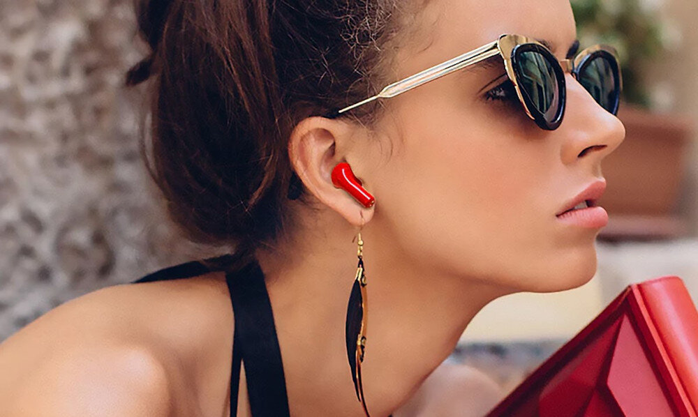 Słuchawki douszne HAPPY PLUGS Joy - Lekkie jak piórko, kobieta w okularach przewsłonecznych z słuchawkami w uszach