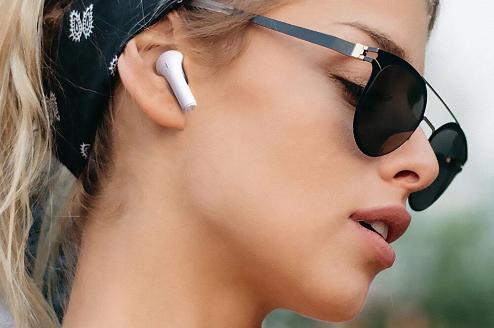 Słuchawki douszne HAPPY PLUGS Joy - Ekspresowe ładowanie, kobieta w okularach przewsłonecznych z słuchawkami w uszach