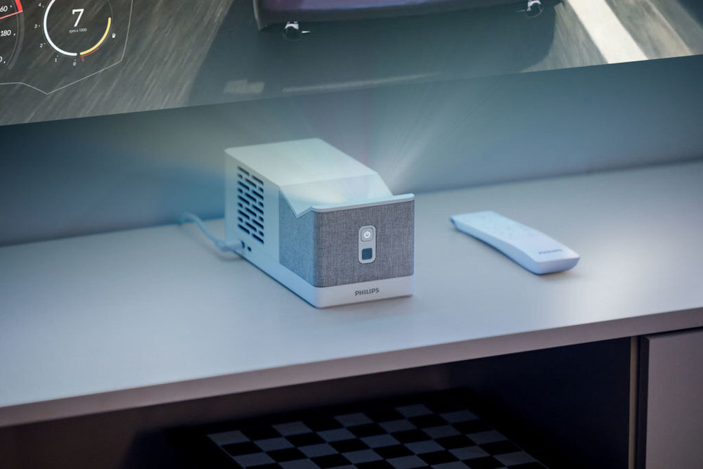 Projektor PHILIPS Screeneo UL5 Smart - Bezprzewodowa łączność, projektor z pilotem stojący na szafce rtv, wyświetlający obraz