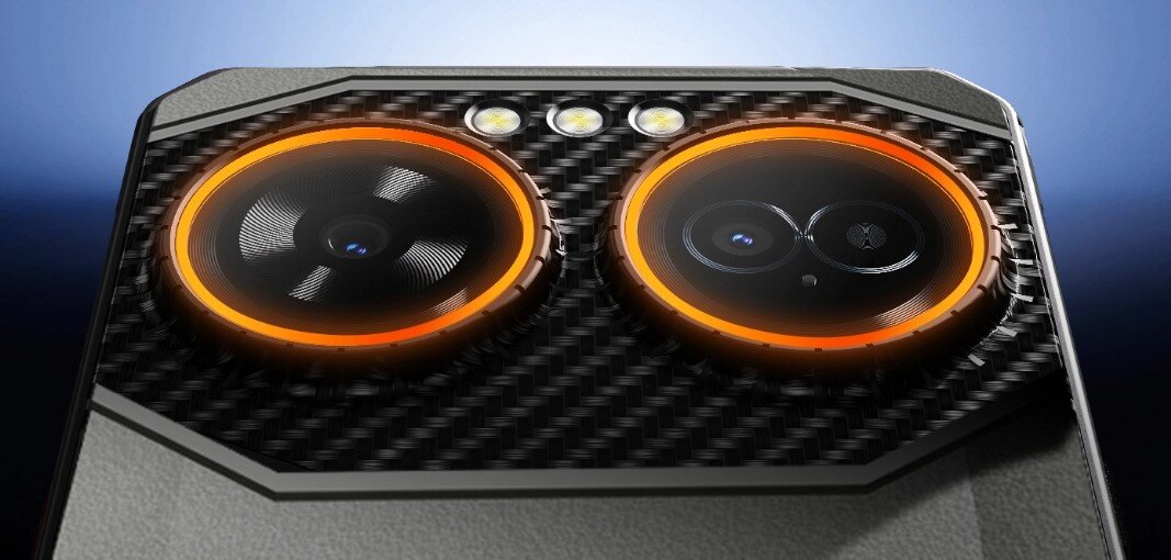 Zbliżenie na tylną część smartfona z dwoma dużymi obiektywami aparatu otoczonymi pomarańczowymi pierścieniami i trzema małymi diodami LED powyżej. Powierzchnia wokół obiektywów ma wzór przypominający włókno węglowe.