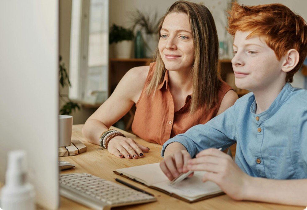 Router TP-LINK Deco BE25 Kobieta oraz chłopiec siedzą przed komputerem, patrząc na ekran monitora, kontrola rodzicielska, funkcje