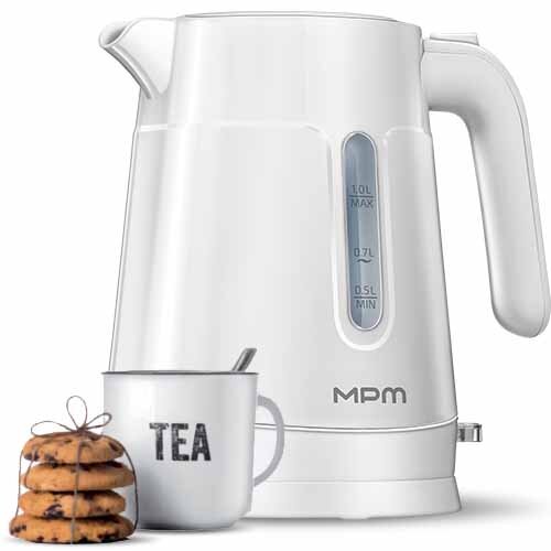 Biały czajnik elektryczny z przezroczystym wskaźnikiem poziomu wody i logo MPM. Obok znajduje się kubek z napisem \'TEA\' oraz stos ciastek przewiązanych sznurkiem.