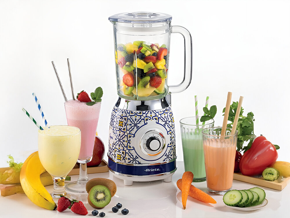 Blender kielichowy ARIETE 583 Capri białe tło blender przeźroczysty kielich pokrętło wzorzysta obudowa biało niebieska z elementami żółtego owoce wewnątrz blendera kolorowe koktajle w szklankach owoce i warzywa zdrowe potrawy i napoje odżywcze smoothie koktajle mleczne kremowe zupy pokrojenie składników umieszczenie ich w pojemniku wybranie odpowiednich ustawień prędkosci pełne witamin dania