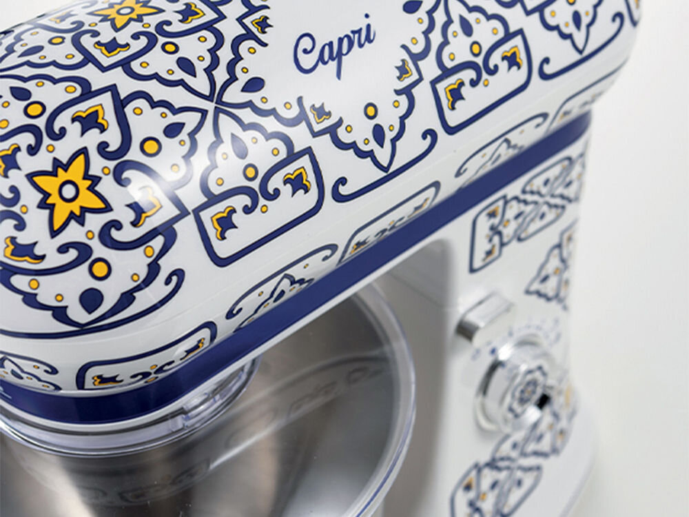 Robot kuchenny planetarny ARIETE 1588 Capri 2400W wzorzysta obudowa biało niebieska elementy żółtego metalowa misa jasne tło potężny silnik o mocy 2400 W łatwość precyzja przygotowanie delikatnych kremów wyrabianie ciężkich ciast drożdżowych wydajność optymalne efekty