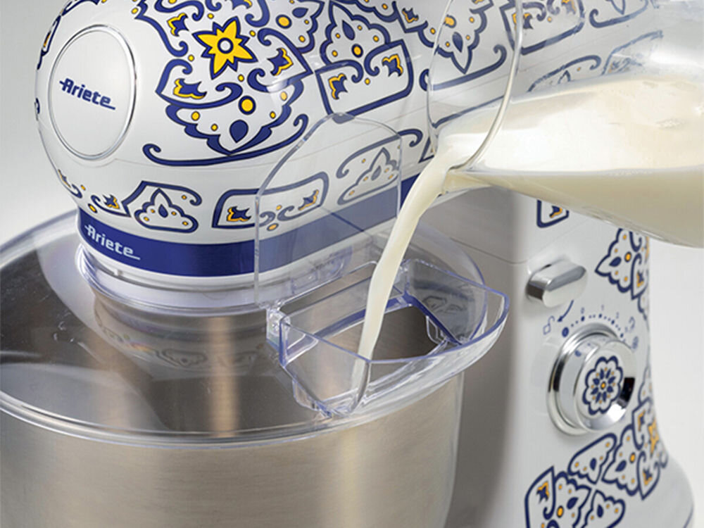 Robot kuchenny planetarny ARIETE 1588 Capri 2400W białe tło wzorzysta obudowa osłona wlewanie mleka do otworu Metalowa misa o pojemności 5,5 l ciasto z ponad kilograma mąki funkcjonalny pomocnik duże rodzinne uroczystości osłona przeciw chlapaniu z wygodnym otworem na składniki solidne przyssawki misa akcesoria możliwość mycia w zmywarce